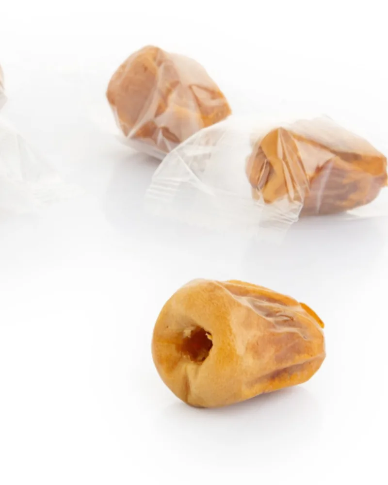 A pitted Sukkari date beside dates each in its own wrapper